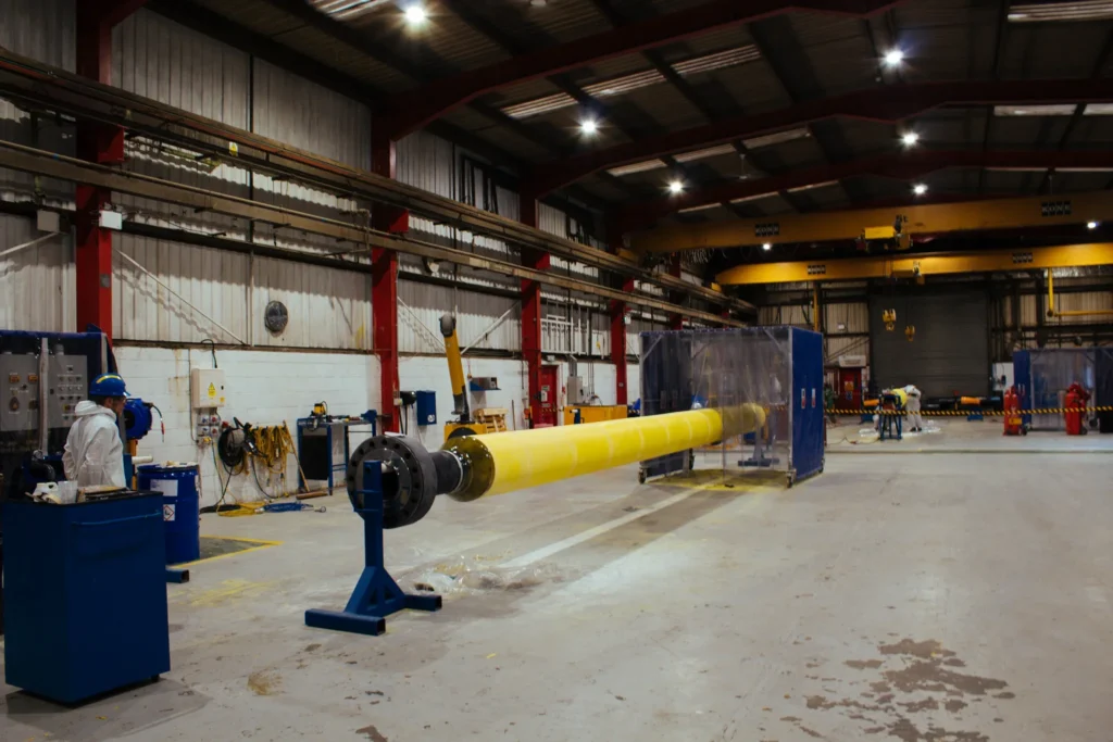 Technicians applying yellow polyurethane thermal insulation to a pipe in LJF Custom Coatings facility